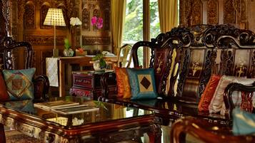 A room with ornate furniture, a table with books, and a vase with flowers.