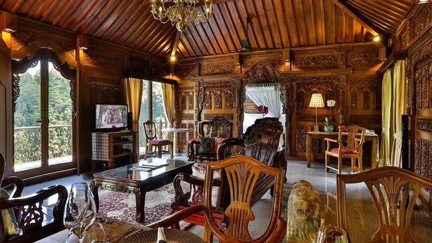 Una habitación lujosa con muebles de madera ornamentados, un candelabro y un ventanal que ofrece vistas panorámicas.