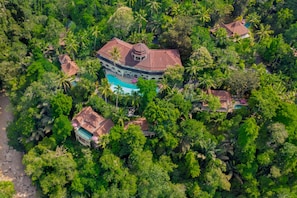 Un gran complejo turístico con varias edificaciones, una piscina central y exuberantes jardines tropicales.
