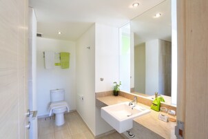 A modern bathroom with a toilet, sink, and mirror.