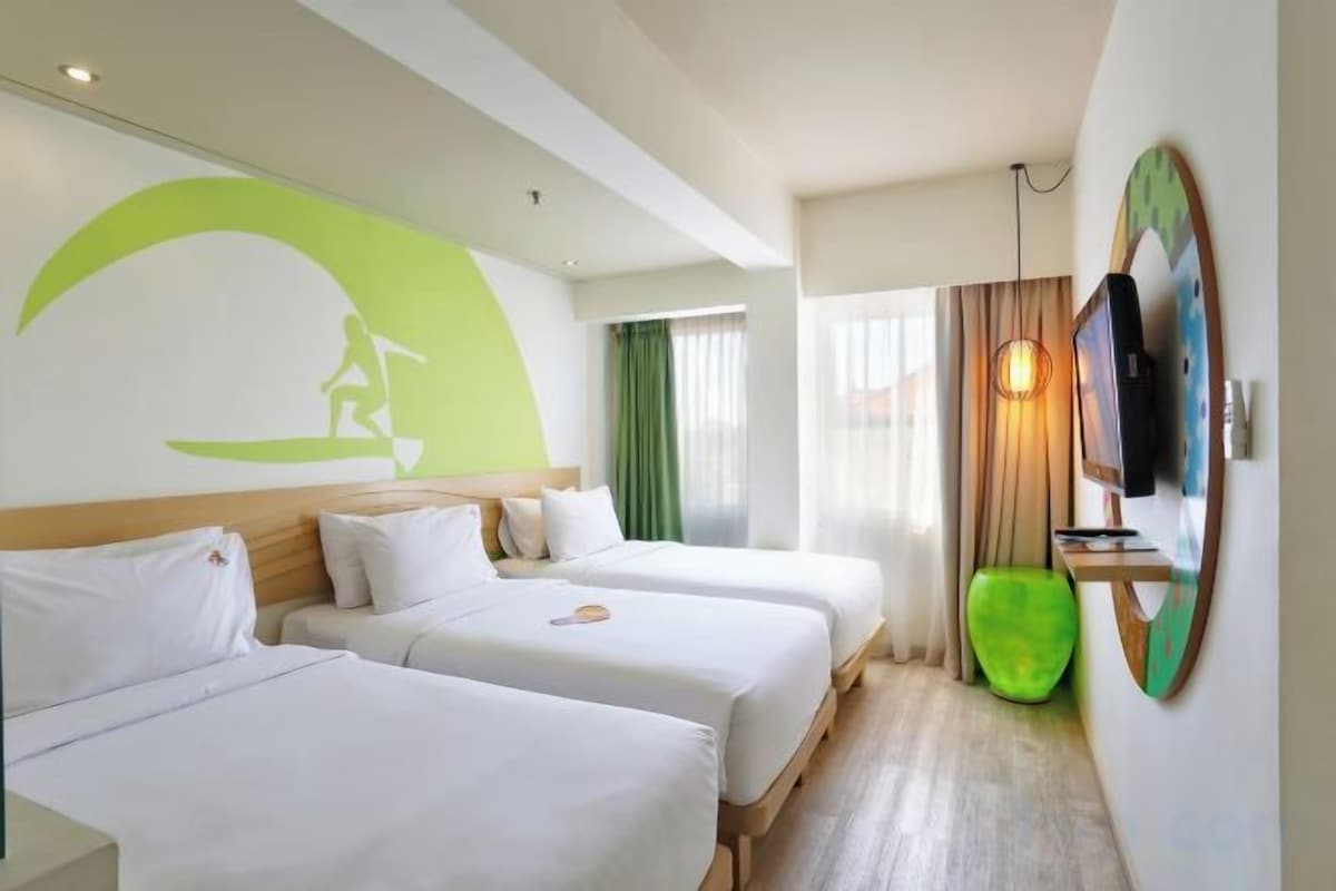 Habitación de hotel con dos camas, un televisor, una silla verde y un ventanal grande.