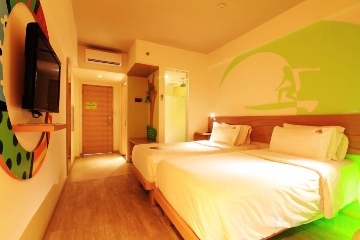 A hotel room with a bed, a television, and a wall-mounted artwork.