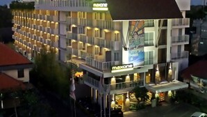 Un hotel de varios pisos con un llamativo letrero 'maxone', que presenta un diseño moderno con balcones y un atrio central.