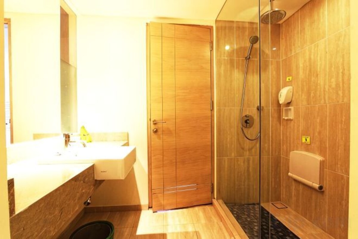 A bathroom with a wooden door, a sink, a mirror, and a shower area.