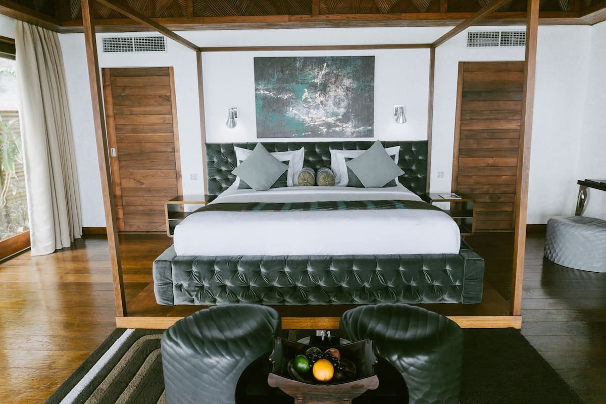Un dormitorio moderno con una cama grande, cabecera de madera y un adorno en la pared.