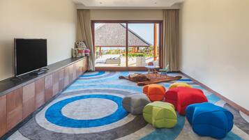 Relax in this stylish living room with a flat-screen TV, comfortable seating, and a sliding door to an outdoor area with a view.