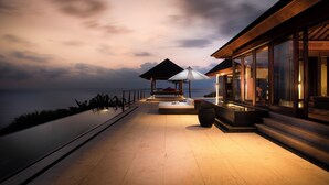 Una zona relax esterna moderna con piscina, sedute e ombrelloni.