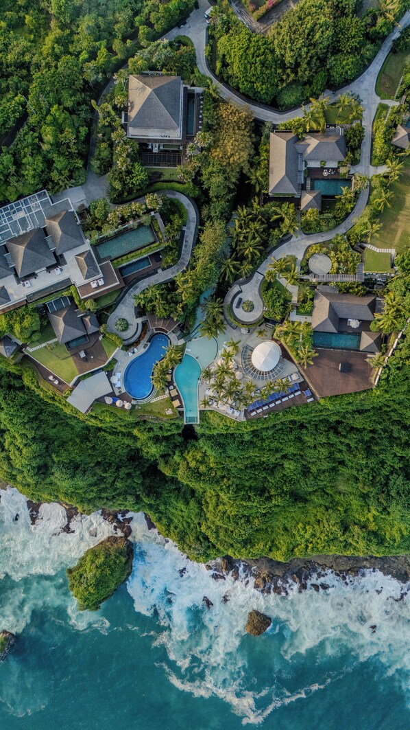 Vista aérea de un complejo turístico con varias construcciones, una piscina grande y acceso a la playa.