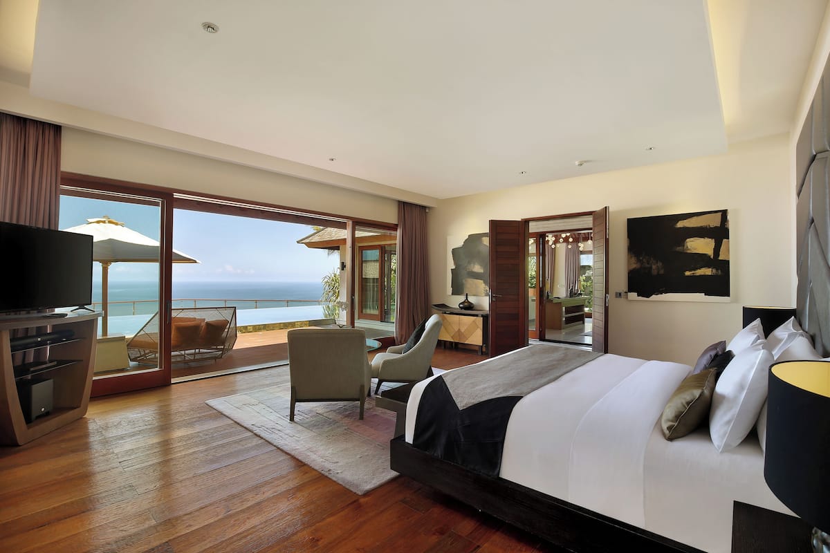 Una habitación de hotel moderna con una cama grande, televisión, escritorio y balcón con vista al mar.