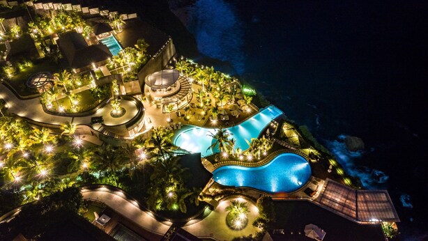 Vista aerea di un resort con piscine, palme e accesso diretto alla spiaggia.