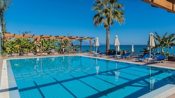 Una piscina al aire libre, sombrillas, sillones reclinables de piscina