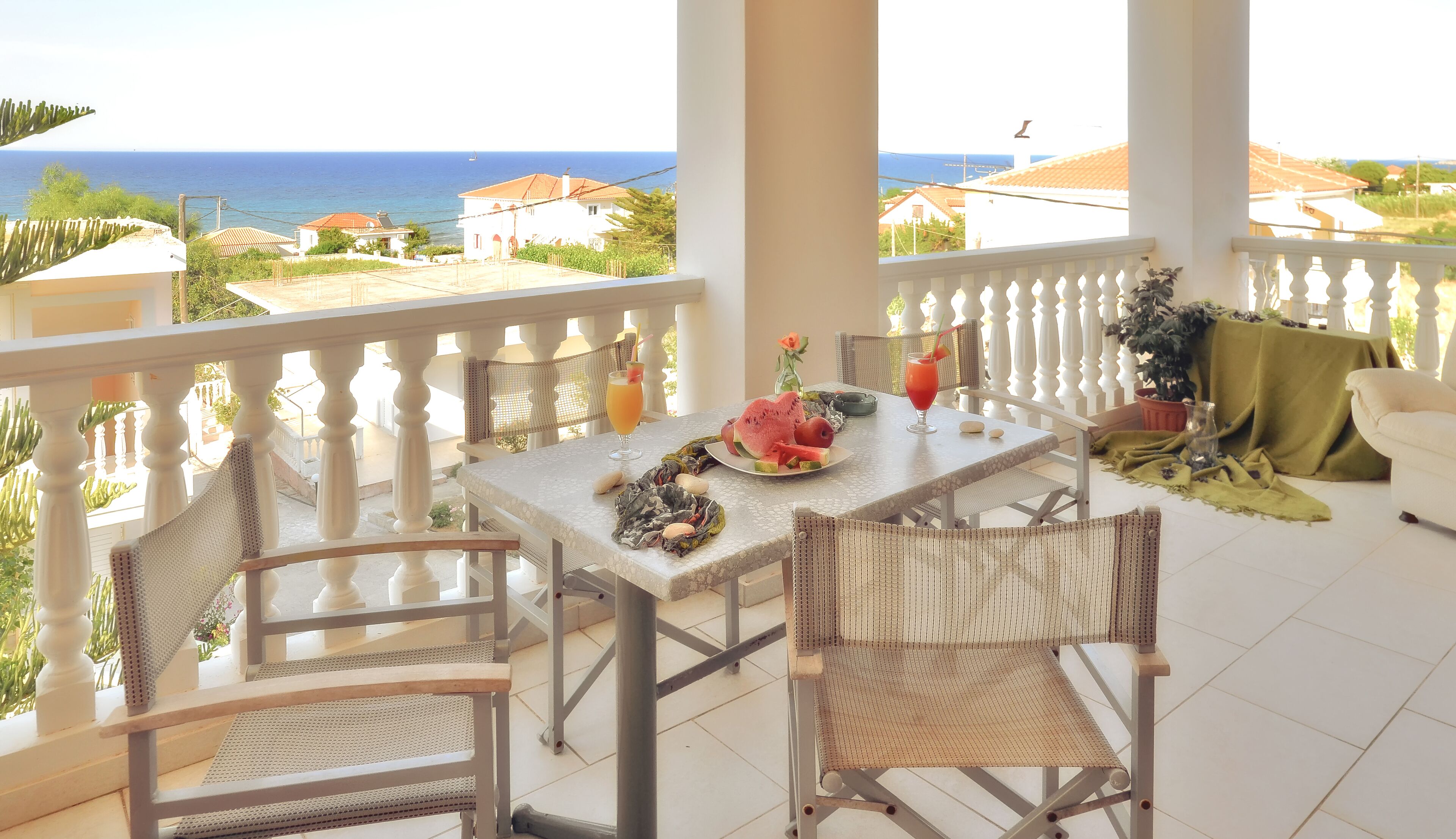 Un balcón con una mesa lista para dos personas, con vistas al mar.
