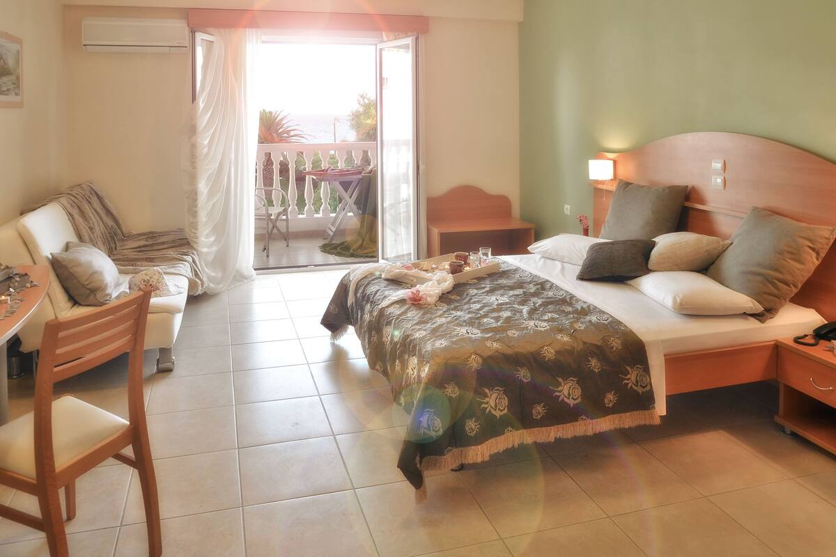 Une chambre d’hôtel équipée d’un lit, d’un bureau, d’une chaise, d’une table de chevet et offrant une vue sur l’extérieur.