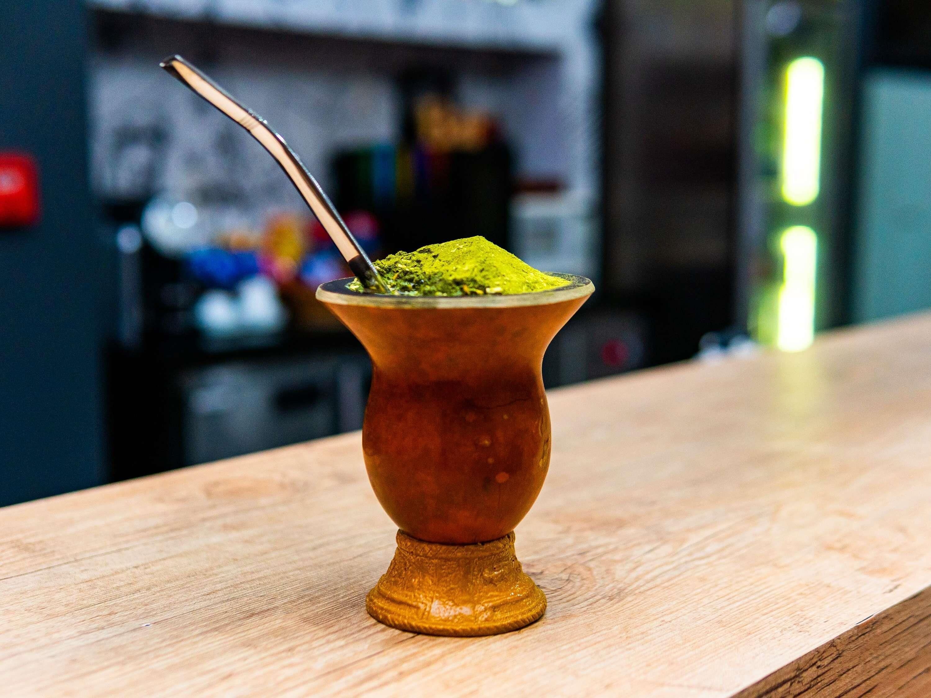 Une tasse traditionnelle de yerba mate avec une cuillère, posée sur une surface en bois.