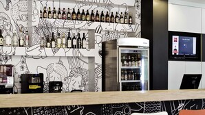 Zona de bar con una variedad de botellas de licor, un refrigerador y una pantalla digital que muestra información.
