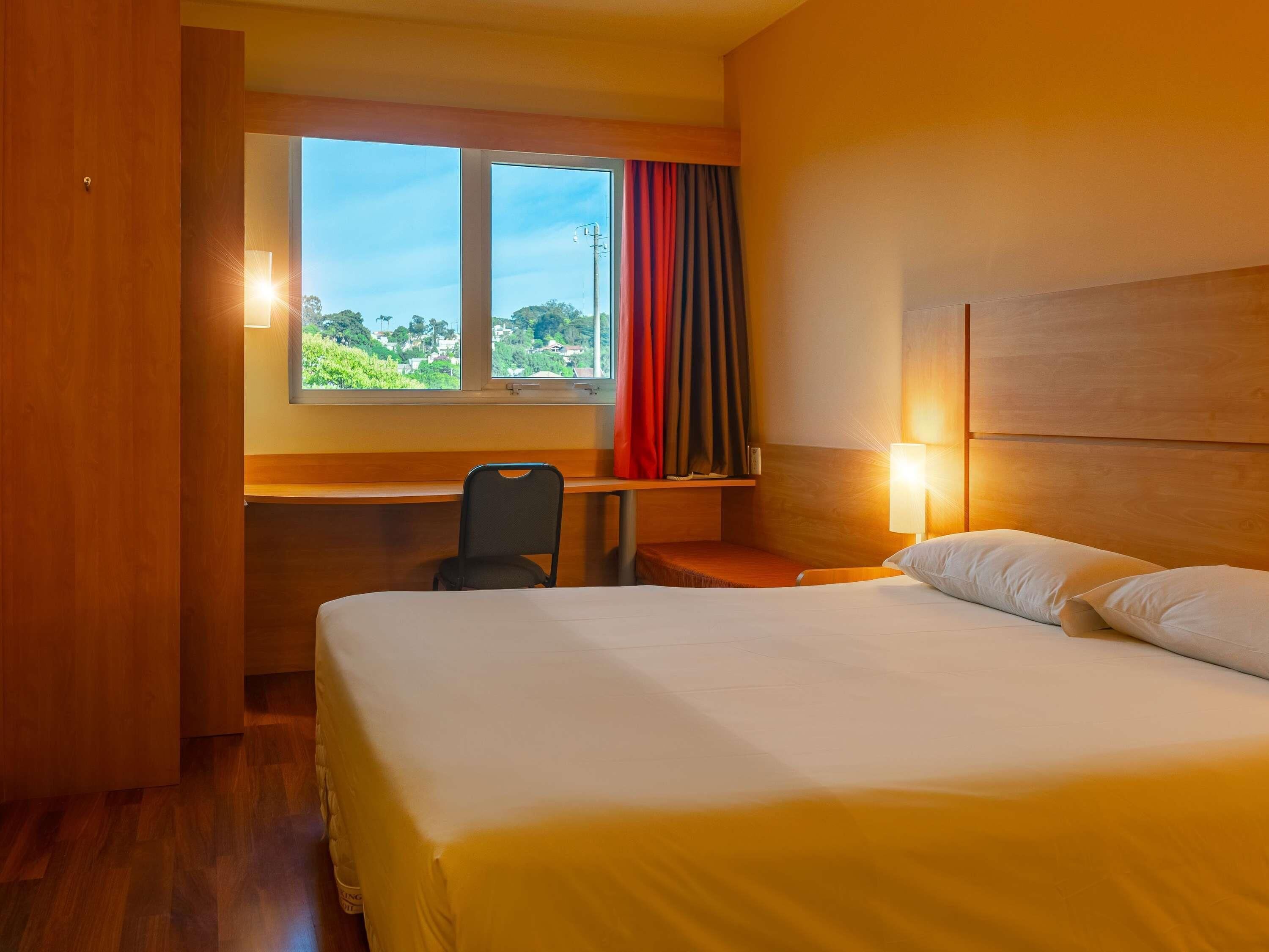 A hotel room with a bed, a desk, and a chair.