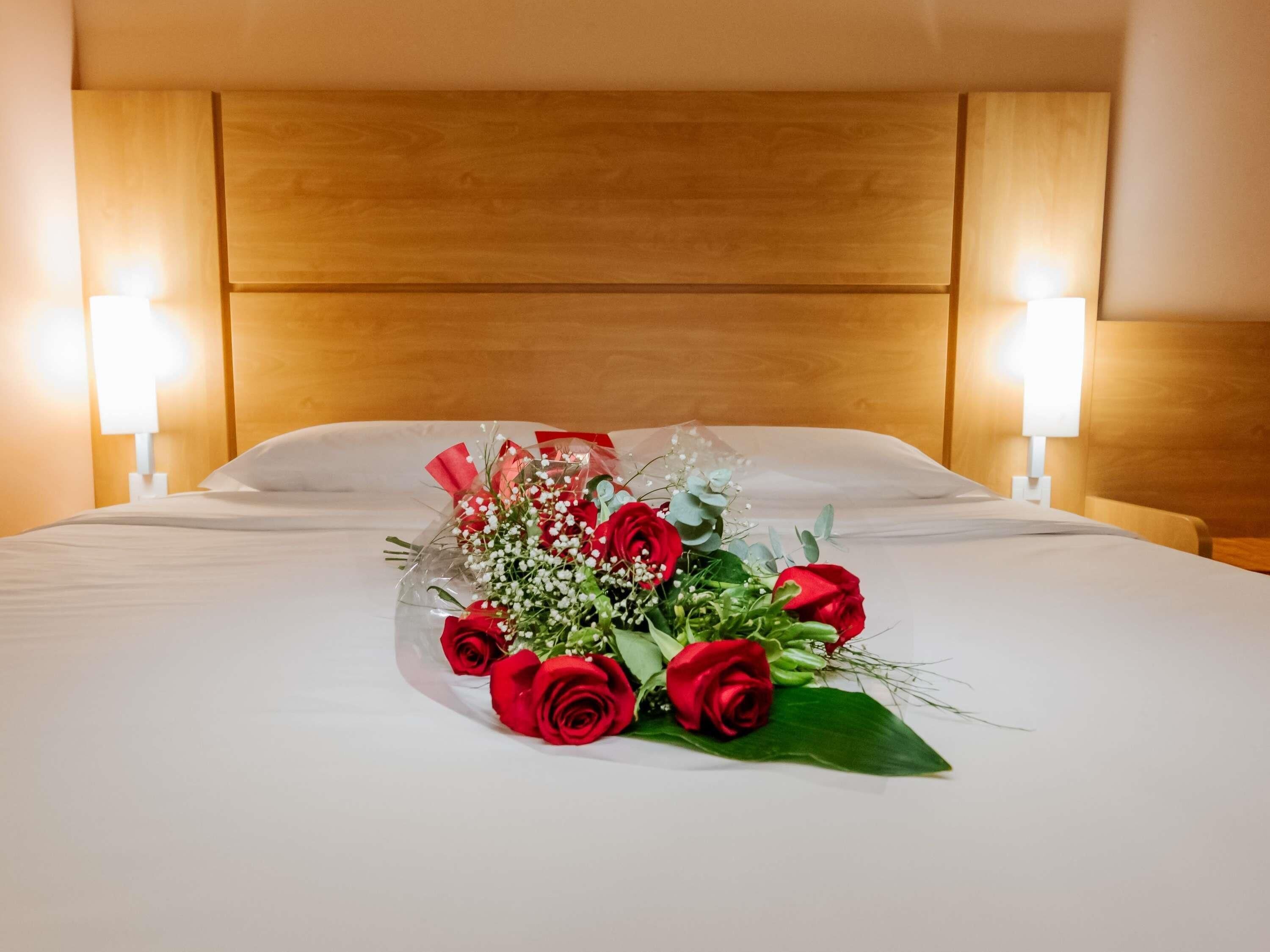 Una habitación de hotel con una cama bien hecha, un cabecero de madera y lámparas de noche.