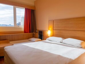 Une chambre dâhĂŽtel avec un grand lit, une table de chevet, une fenĂȘtre avec des rideaux et une vue sur la ville.