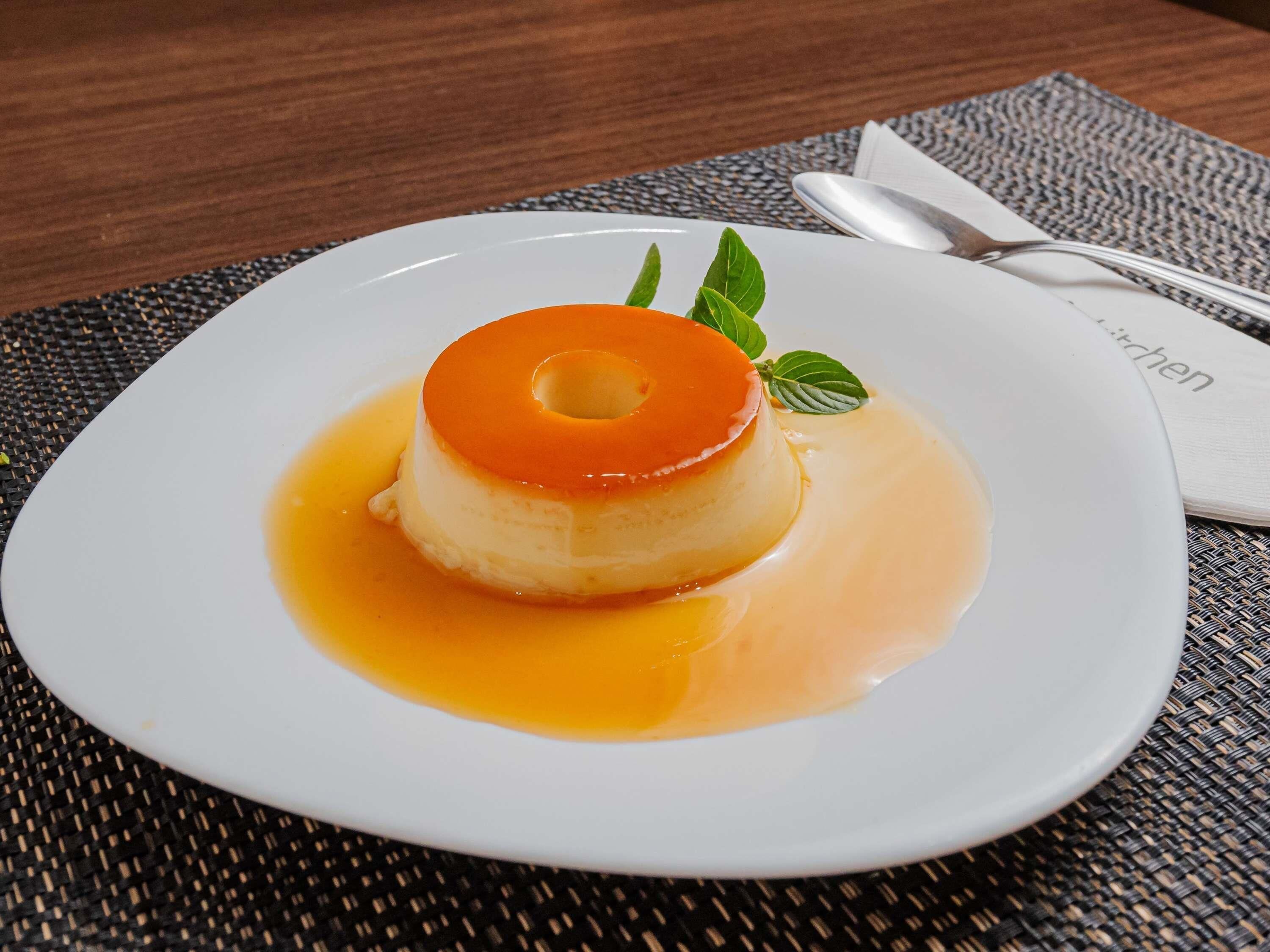 Sobremesa em um prato branco, com uma colher e guardanapo ao lado.