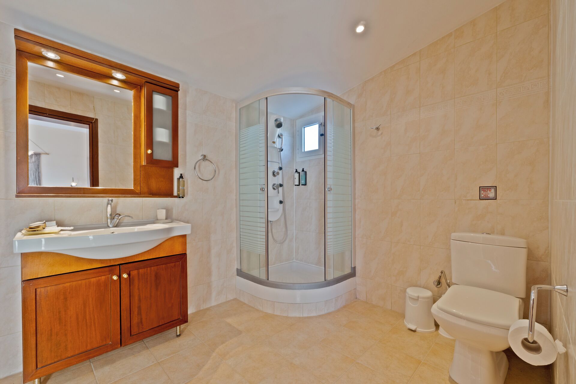 A modern bathroom with a glass-enclosed shower, a wooden vanity with a mirror, and a toilet.