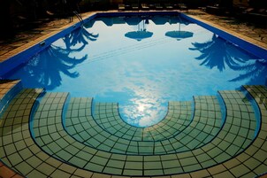 Una piscina al aire libre, sombrillas, sillones reclinables de piscina