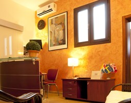 Una camera d'albergo con scrivania, sedia, letto e un quadro astratto incorniciato appeso al muro.