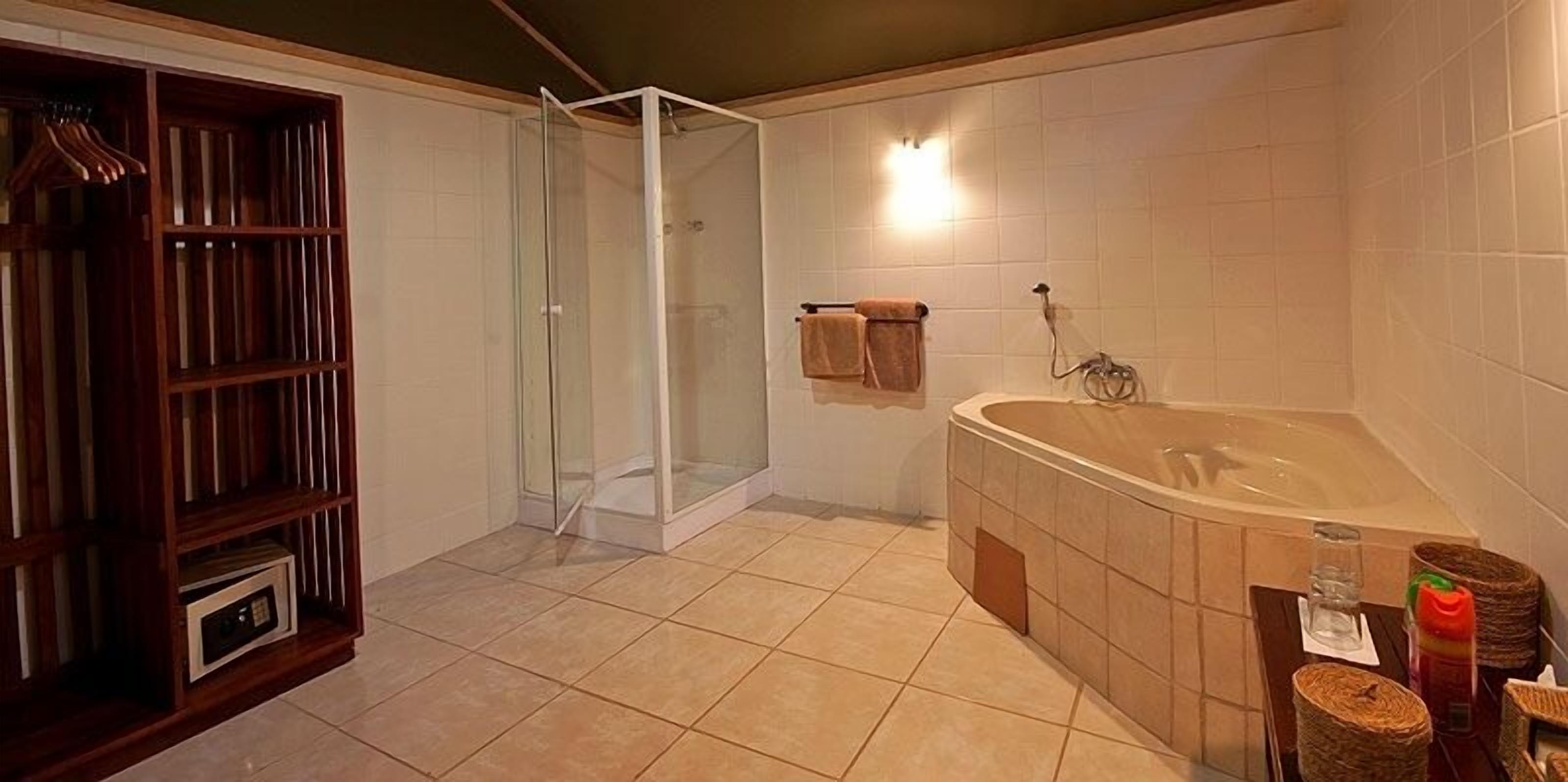 Ein Badezimmer mit einer gläsernen Duschkabine, einer großen Badewanne und einem Holzboden mit Handtüchern.