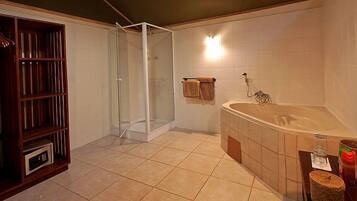 Ein Badezimmer mit einer gläsernen Duschkabine, einer großen Badewanne und einem Holzboden mit Handtüchern.