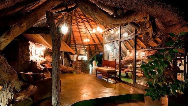 Un intérieur rustique avec un plafond en bois, des murs en pierre et une cloison en verre.