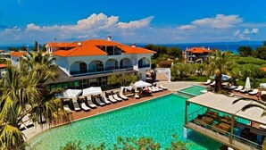 A resort with a pool, lounge chairs, and a building with a red roof. - Flegra Palace (Kassandra)