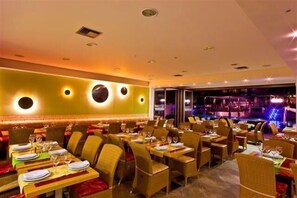 Un restaurant doté de nombreuses tables, de chaises et d’un bar.