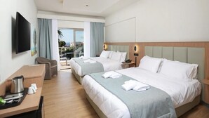 A hotel room with two beds, a desk, a chair, a TV, and a balcony with a view. - Flegra Palace (Kassandra)