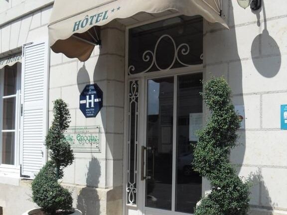 A hotel entrance with a sign indicating a handicap accessible entrance, a large awning, and two potted plants.