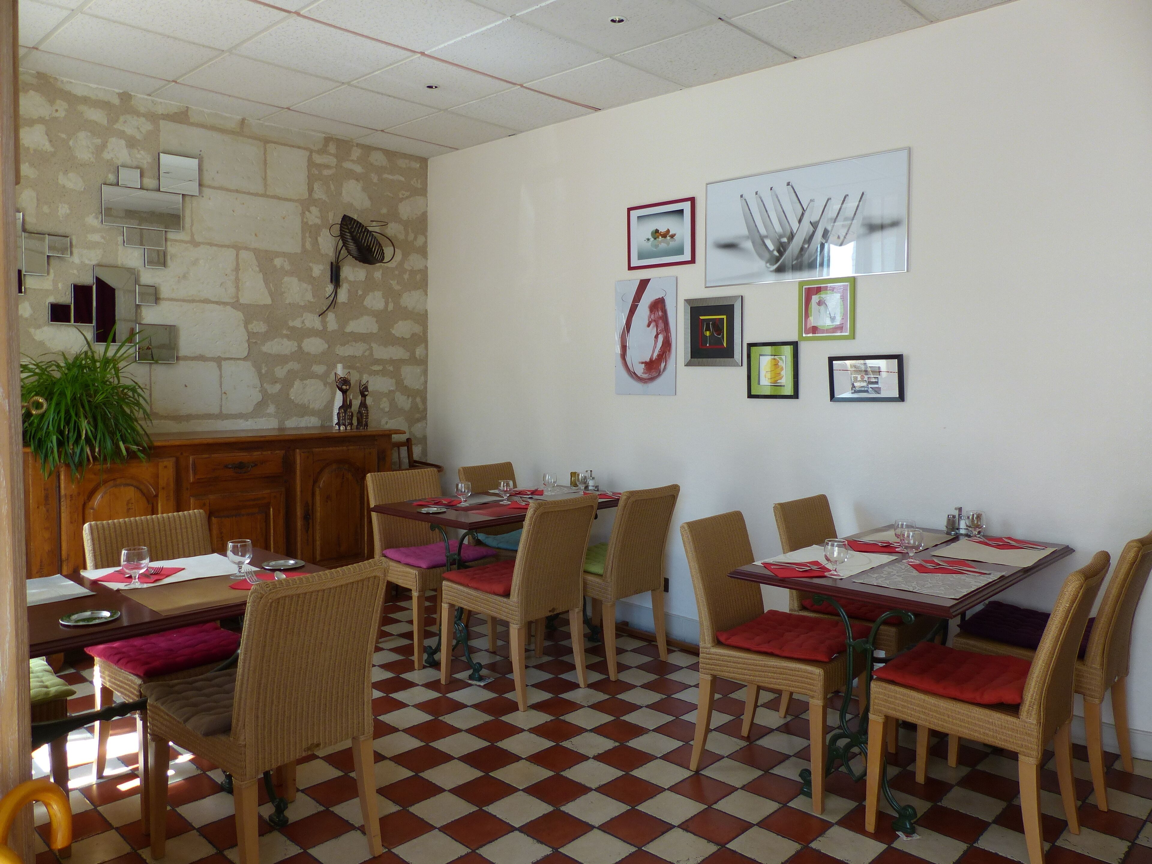 A dining area with checkered flooring, wicker chairs with red cushions, and a wooden table.