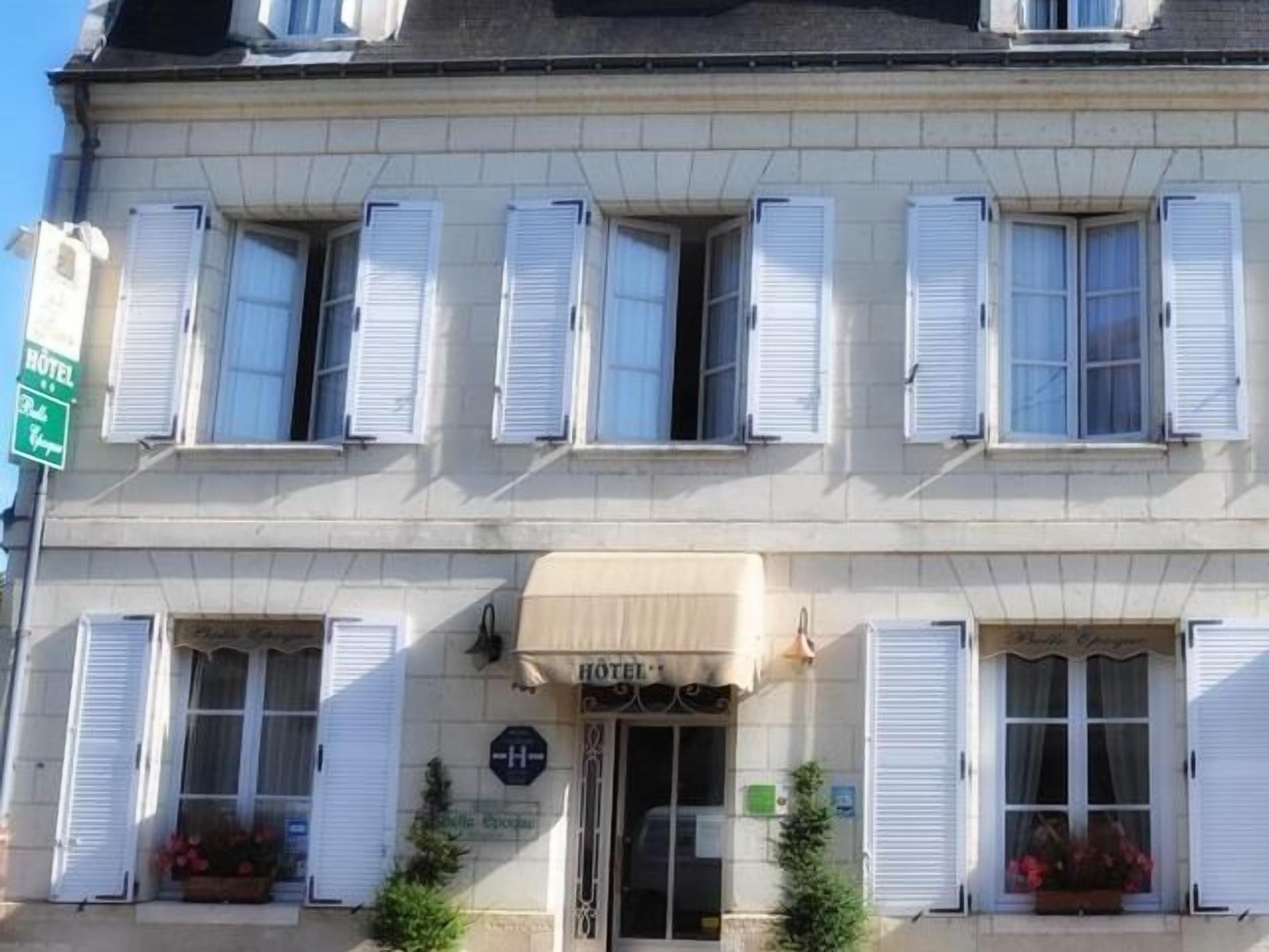 A hotel with a classic facade, multiple windows with shutters, and a sign indicating it is a hotel.