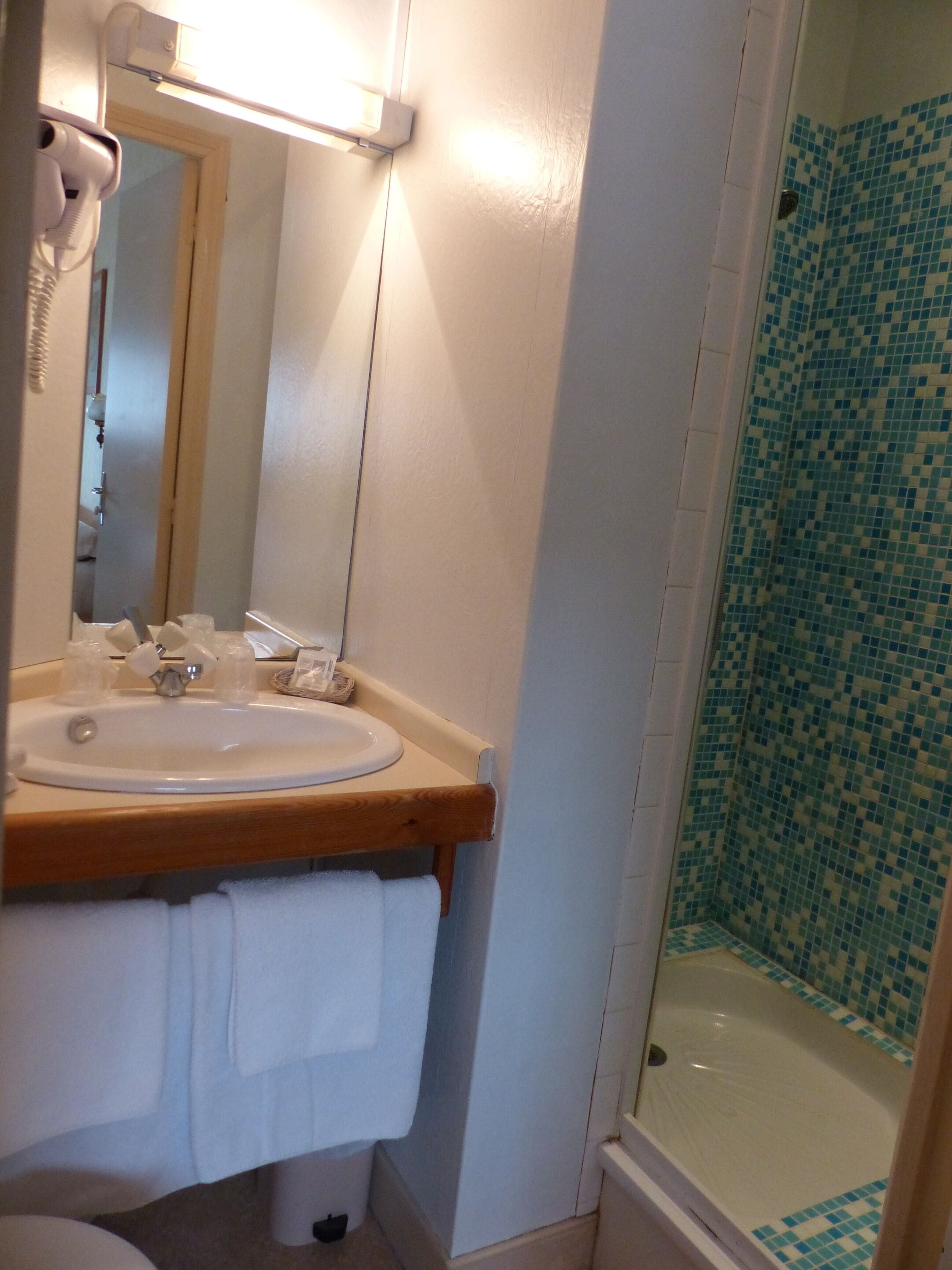 A bathroom with a sink, mirror, and a shower with mosaic tiles.