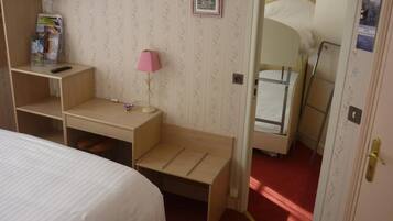 A bedroom with a bed, a desk with a lamp, a TV mounted on the wall, and a bunk bed.