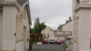 A narrow street with parked cars and a building with a sign that reads "Hotel." - Hôtel Belle Epoque (Chinon)