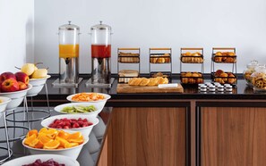 Un buffet de petit-déjeuner proposant une variété de fruits, de viennoiseries et de boissons.