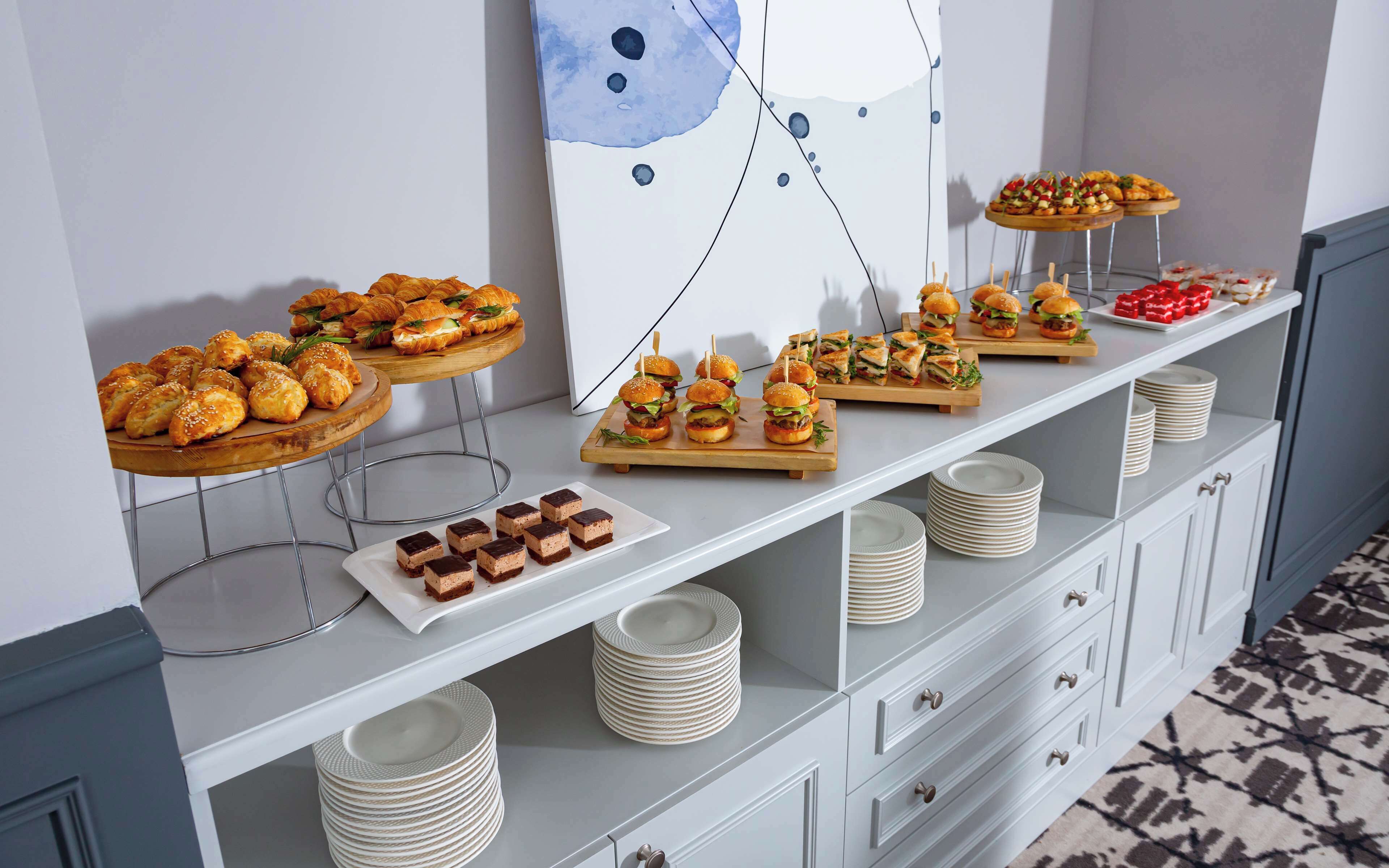 A buffet table with various food items and stacked plates.
