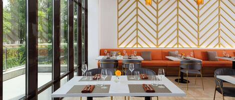 A modern dining area with a white table, black chairs, and a chevron-patterned wall.