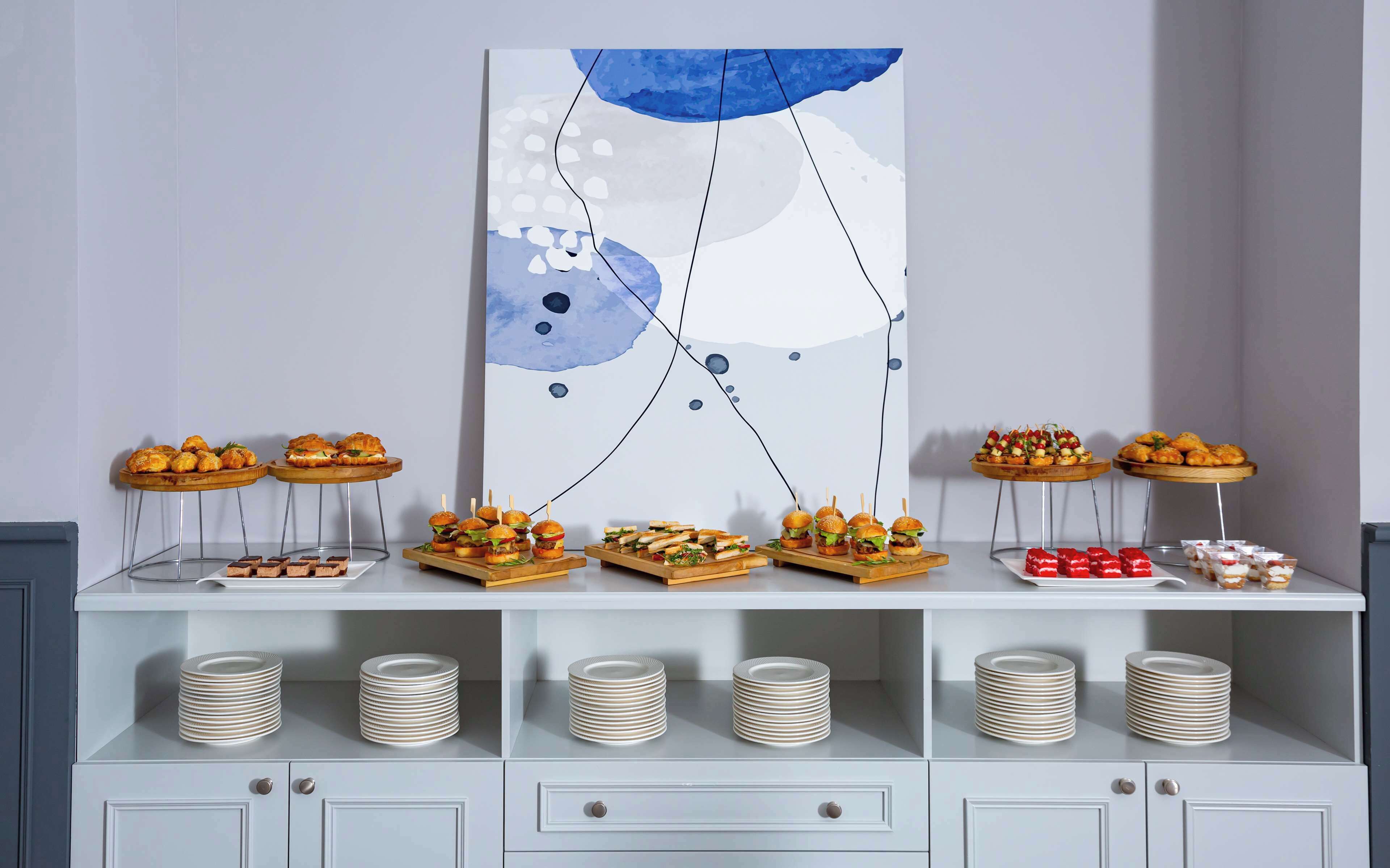 Un buffet proposant une variété de plats et des assiettes empilées sur un meuble blanc.