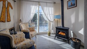 A cozy living room with a fireplace, patterned furniture, and a large window with curtains. - Alaçatı Sultan Konak Butik Otel (Cesme)