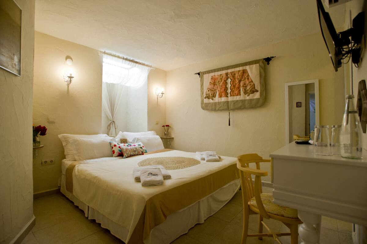 A hotel room with a bed, a chair, a desk, and a mirror.