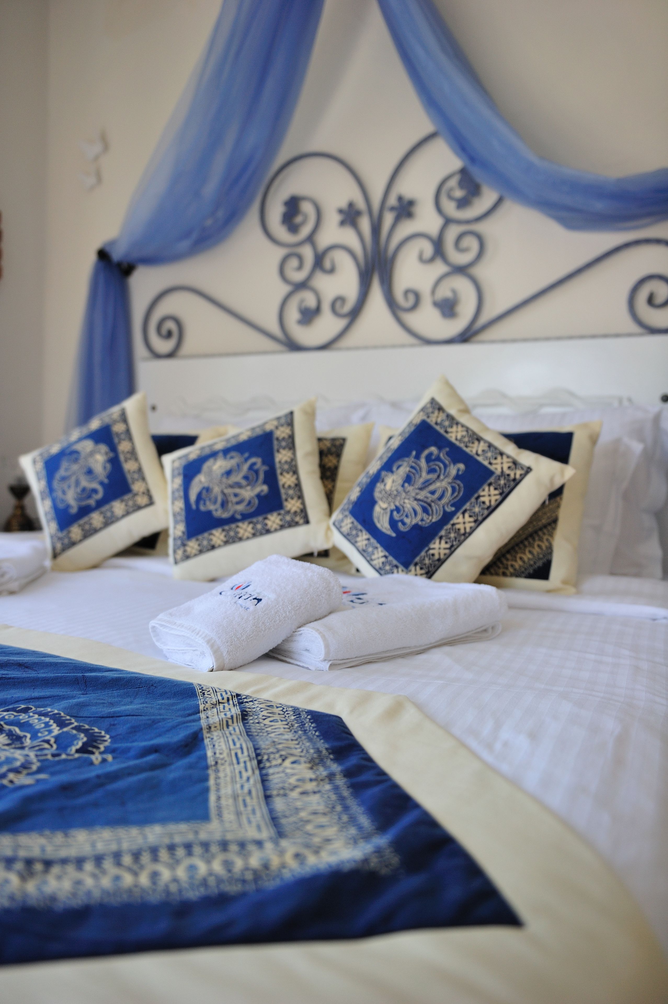 A neatly made bed with blue and white pillows, a blue and white bedspread, and a canopy.