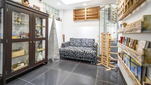 Een woonkamer met een bank, een kast met glazen deuren, een ladder en een wand met boekenplanken.
