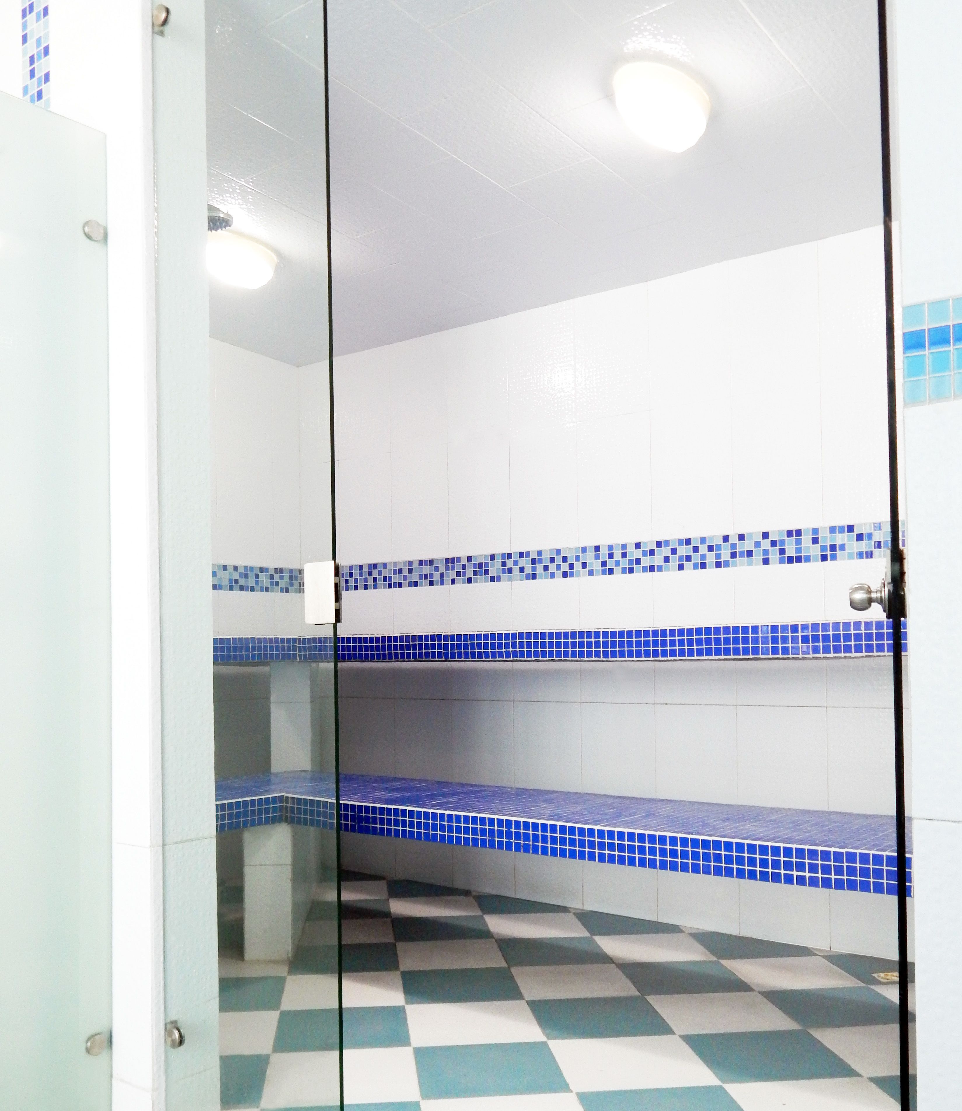 A bathroom with white walls, blue-tiled shelves, and a checkered floor.
