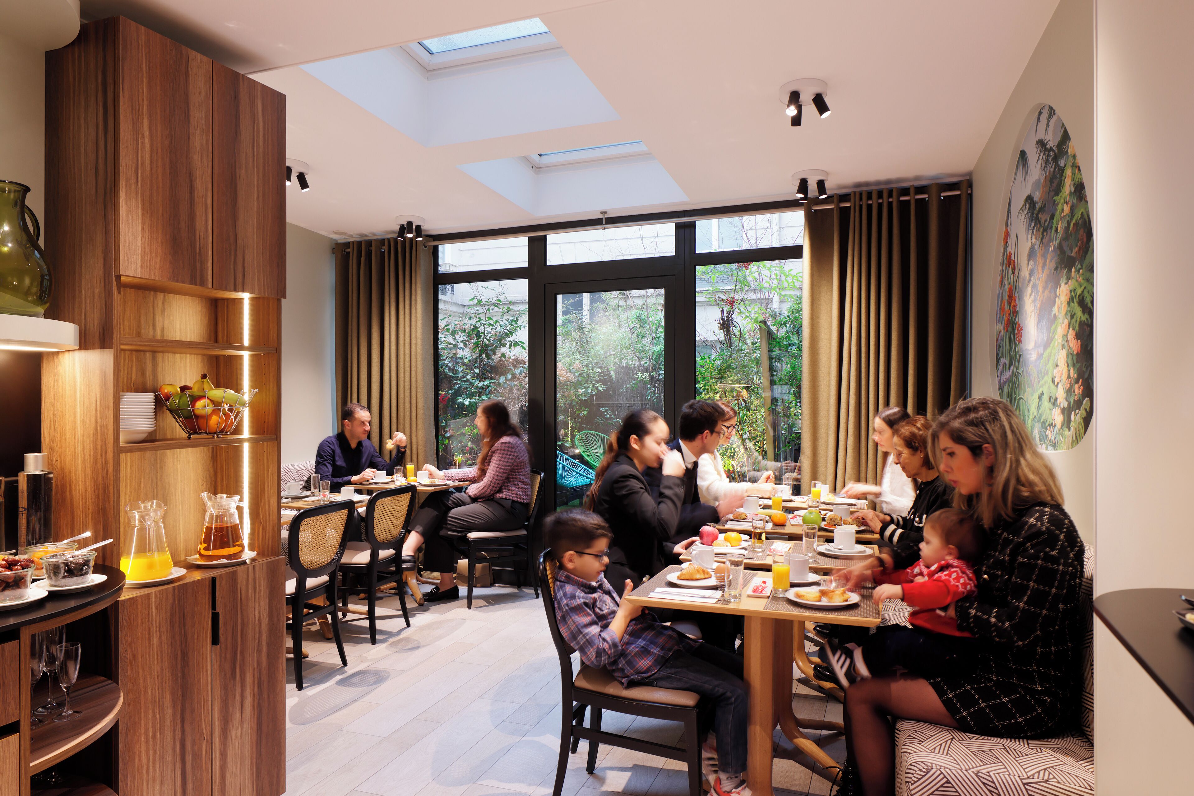 Un espace de restauration moderne, baigné de lumière naturelle grâce à des puits de lumière, offrant une variété de possibilités d’assise et donnant sur un paysage verdoyant.