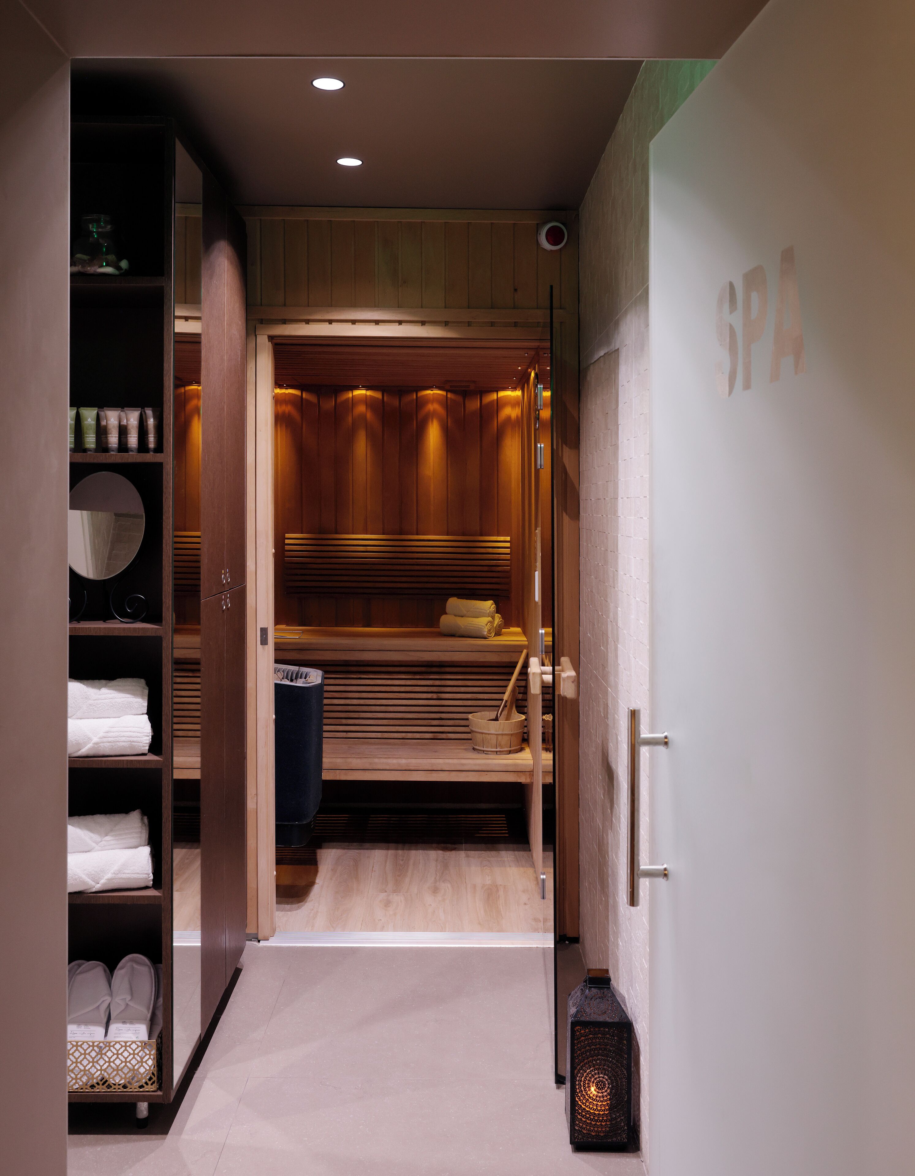 A spa room with wooden paneling, a bench, towels, and a sauna.