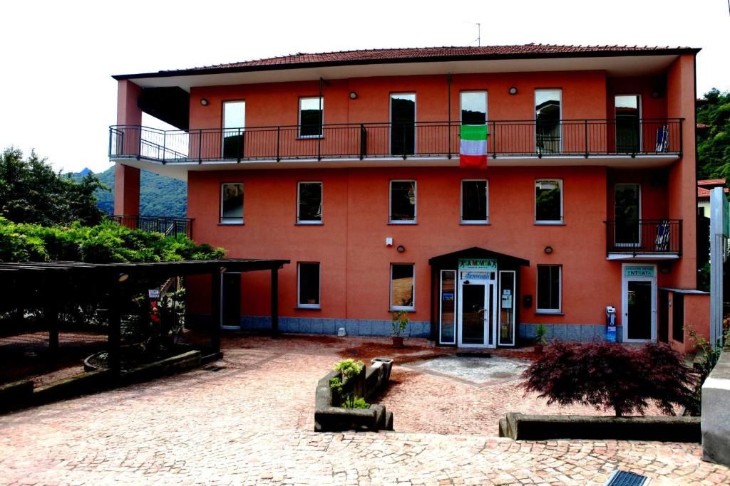 Un edificio a due piani con facciata rossa, un balcone al piano superiore e un piccolo ingresso con un cartello.